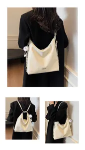 Détail du sac seau crème avec bandoulière chaîne et pendentif en peluche sur manteau noir