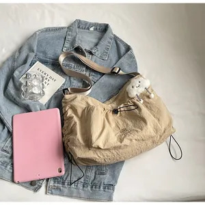 Detail of beige nylon crossbody bag with side drawstring and plush cloud keychain
