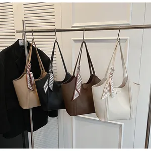 Detail von vier Kunstleder-Tote-Bags mit modischen Karoschals an metallischen Kleiderbügeln