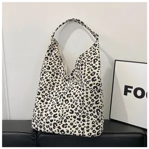 Close-up of the large leopard print canvas tote bag on a black leather bench