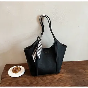 Detail der schwarzen Tote Bag aus genarbtem Leder mit goldenem Logo und Seidenschal