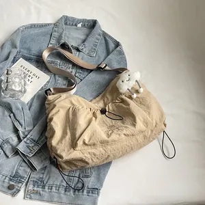 Khaki nylon drawstring crossbody bag with cloud pendant on denim background