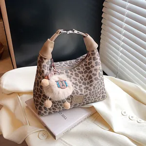 Sac hobo léopard avec anse en cuir et breloque peluche sur fond de blazer beige