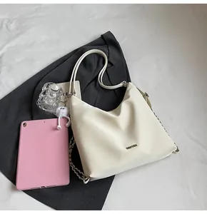 Détail du sac Hobo crème avec chaîne en métal, logo et petit accessoire en peluche