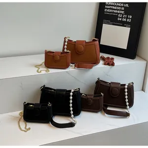 Détail de sacs à bandoulière tendance en cuir marron et noir avec chaînes perlées