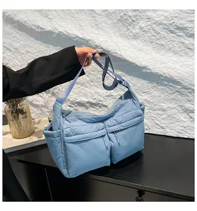 Détail d'un sac à bandoulière en nylon matelassé bleu clair avec plusieurs poches