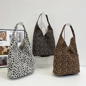 Three leopard print hobo bags in beige, brown, and orange hanging on a metal stand