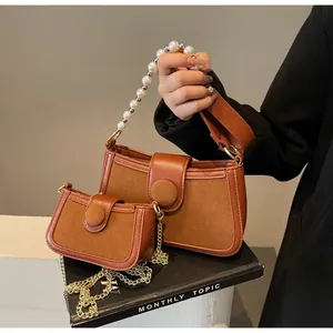 Détail du sac bandoulière marron en daim avec poignée perle et chaîne dorée