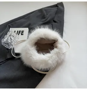 Draufsicht auf flauschige weiße Kunstfell-Eimertasche mit Perlen auf grauem Blazer