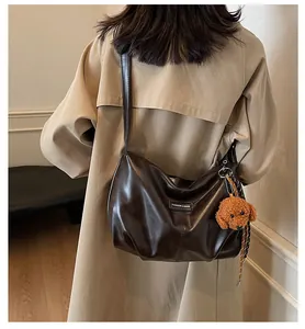 Close-up of dark coffee shoulder bag featuring a cute plush teddy bear charm detail
