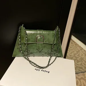 Dunkelgrüne Vintage Schultertasche mit Nieten und Kettenträger auf einem Podest
