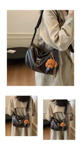 Detail of dark brown faux leather tote with pleated texture and plush puppy charm