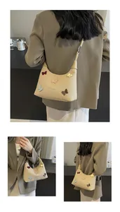 Tripla vista di una borsa a mezzaluna beige con applicazioni di farfalle colorate