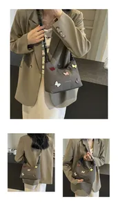 Dettaglio ravvicinato di toppe a farfalla colorate su una borsa a mezzaluna in nylon marrone