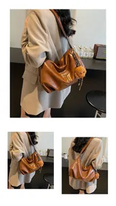 Detail of caramel brown hobo bag featuring a leather logo tag and cute plush bear charm