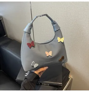 Dettaglio della borsa a mezzaluna in tela grigia con cinque farfalle colorate 3D
