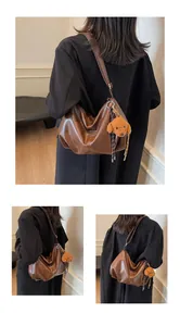 Detail of a brown vintage hobo bag with a cute plush dog charm and branded label