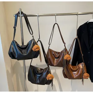 Detail of hobo shoulder bags in multiple colors with plush teddy bear pendants