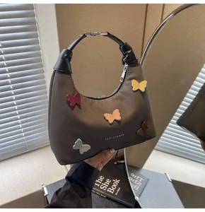 Dettaglio della borsa hobo in tela marrone con applicazioni di farfalle colorate