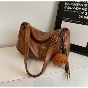 Detail of vintage brown pleated tote bag with plush dog charm and adjustable strap
