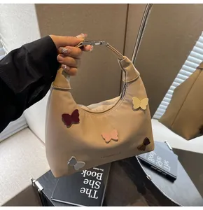 Dettaglio borsa hobo in tela beige con farfalle 3D colorate e fibbia metallica decorativa