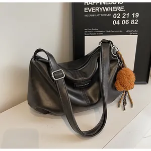 Detail of black pleated shoulder bag featuring fashion leather label and brown teddy charm