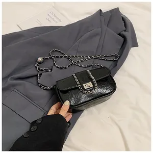Dettaglio mini borsa in pelle cerata nera con chiusura argento e tracolla a catena