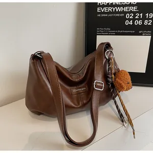 Close-up of brown leather tote bag with FASHION & BAGS tag and cute bear pendant