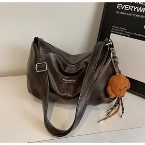 Detail of dark brown faux leather tote with adjustable strap and plush poodle charm