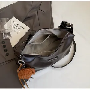 Interior view of brown tote bag with zipper pockets and plush bear pendant detail