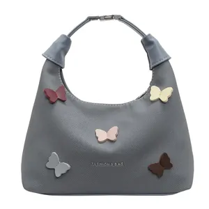 Borsa a mano in tela grigia con farfalle 3D colorate e manici in pelle su sfondo bianco