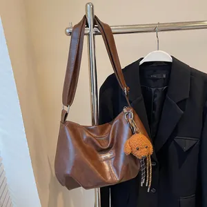 Brown vintage pleated hobo bag with wide shoulder strap and cute puppy charm accessory