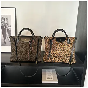 Detailansicht großer Leopard-Print-Tote-Taschen mit Ledergriffen und verspielten Anhängern