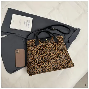 Detailansicht der Leopard-Print-Tasche mit schwarzen Ledergriffen und langem Schultergurt