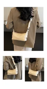 Detail view of cream leather shoulder bag showing wide adjustable strap and silver zippers