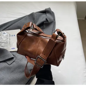 Detail of retro brown cylinder shoulder bag featuring silver buckle and wide strap