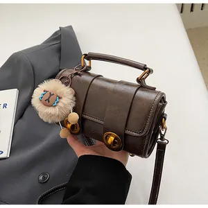 Details der kaffeebraunen Boston-Tasche mit goldenen Drehverschlüssen und Plüsch-Anhänger
