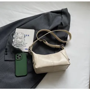 Top view of beige retro crossbody bag on a grey blazer with lifestyle props