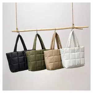 Nahaufnahme gesteppter Daunen-Tote-Bags in Schwarz, Grün, Khaki und Weiß am Holzstab