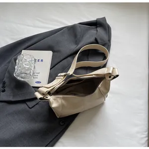Detail of a beige leather underarm bag with zipper closure styled on a grey blazer