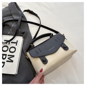 Detail der zweifarbigen Handtasche in Creme und Schwarz mit Goldlogo und rundem Griff