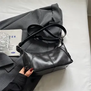 Minimalist black quilted underarm bag with adjustable strap in urban lifestyle setting