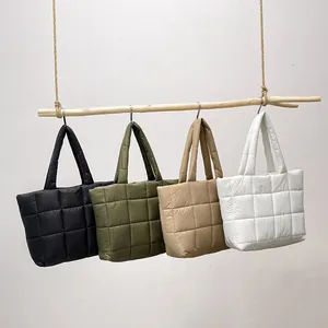 Minimalistische Stepp-Shopper in Schwarz, Grün, Khaki und Weiß an Holzast hängend