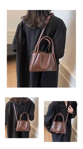 Detail of vintage brown leather handbag with double ring handles and shoulder strap