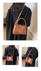 Detail showing vintage brown leather bag with HOCOMI logo and detachable shoulder strap