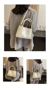 Detail of cream white bucket bag featuring textured PU leather and dual top handles