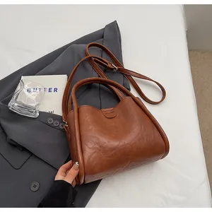 Detail of vintage brown shoulder bag with smooth texture, logo and adjustable strap