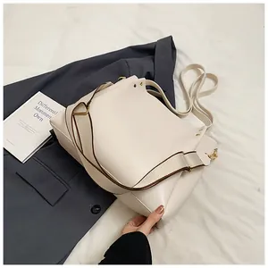 Detail of cream tote bag with broad fabric strap and gold rivets on a grey blazer