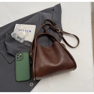 Flat lay of vintage dark brown crossbody bag with handle on grey blazer background