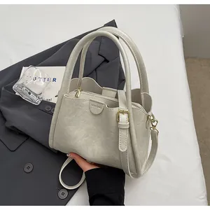 Close-up of light grey leather tote with HOGOMU branding and silver hardware detail